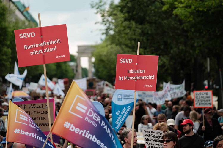 Demonstrierende mit Schildern, im Hintergrund das Brandenburger Tor. 
