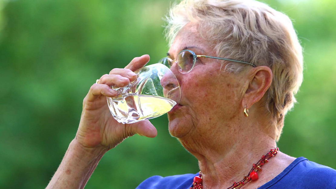 Ältere Frau trinkt Wasser aus einem Glas